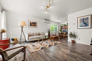 Living room featuring a wall mounted AC, rail lighting, wood finished floors, and baseboards