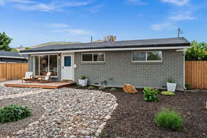 Rear view of house with fence, a wooden deck, and brick siding