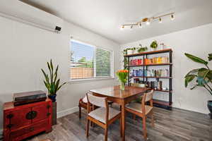Dining room with a wall unit AC & heating, wood finished floors, and baseboards