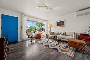Living area featuring a wall mounted AC and wood finished floors