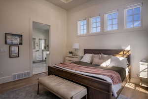 Bedroom with wood finished floors, ensuite bath, and baseboards