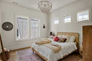 Bedroom featuring baseboards, wood finished floors, and a chandelier