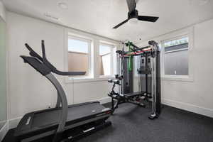 Workout area featuring baseboards, ceiling fan, and a textured ceiling