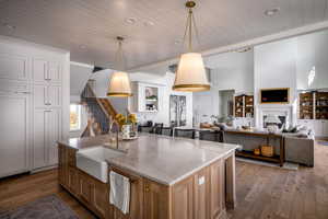 Kitchen featuring wood ceiling, open floor plan, a sink, light wood-type flooring, and pendant lighting