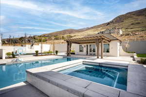 Swimming pool with a mountain view, an in-ground hot tub, french doors, and fence