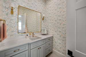 Bathroom with wallpapered walls, baseboards, and vanity