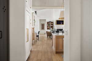 Corridor with light wood-type flooring, wood ceiling, and baseboards