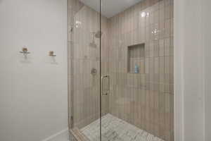Bathroom featuring a shower stall and baseboards