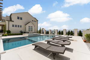 View of swimming pool with a patio area, fence, and a pool with connected hot tub