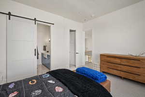 Bedroom with a barn door and light carpet