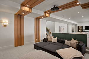 Living area with light colored carpet, baseboards, recessed lighting, and stairway