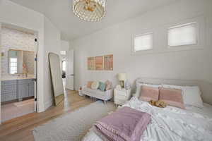 Bedroom featuring light wood-style floors, baseboards, and connected bathroom