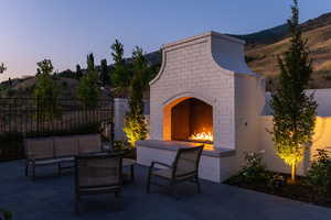 Patio terrace at dusk featuring an outdoor living space with a fireplace, fence, and a mountain view