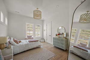Bedroom featuring wood finished floors, a chandelier, and baseboards