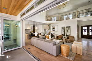 Living area with stairs, wood finished floors, a high ceiling, and recessed lighting