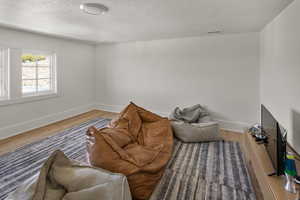 Living room with wood finished floors, a textured ceiling, and baseboards