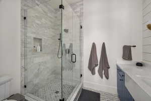 Bathroom featuring a stall shower, toilet, and vanity