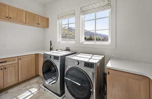 Laundry area featuring washer and clothes dryer, cabinet space, and light marble finish floors