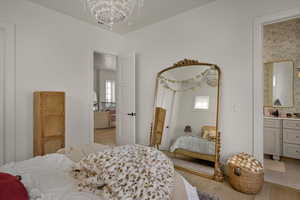 Bedroom with light wood finished floors, multiple windows, and a chandelier
