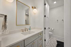 Bathroom featuring vanity, toilet, and baseboards