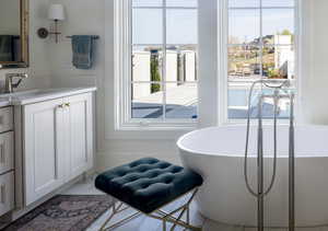Bathroom with plenty of natural light, vanity, a soaking tub, and marble finish flooring