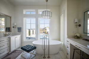 Full bathroom with healthy amount of natural light, vanity, and a soaking tub
