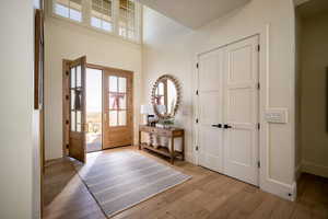Foyer entrance with wood finished floors, baseboards, and a high ceiling