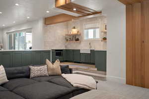Living room featuring recessed lighting, light colored carpet, wet bar, a textured ceiling, and baseboards