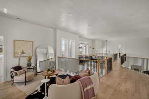 Living area with light wood-style flooring, an upstairs landing, and arched walkways