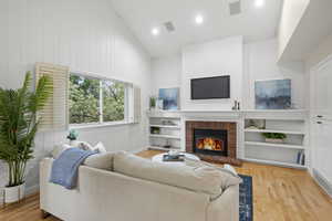 Living area featuring a brick fireplace, wood finished floors, recessed lighting, and baseboards
