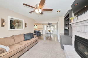 Living area with a ceiling fan, recessed lighting, a fireplace, and wood finished floors