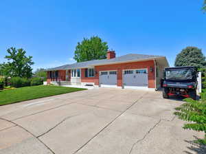 Ranch-style home featuring brick siding, a garage, a front yard, a chimney, and concrete driveway