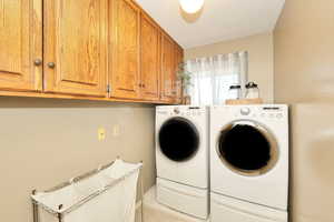Washroom with washer and clothes dryer, cabinet space, and light tile patterned flooring