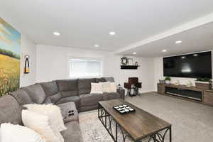 Living room with light colored carpet, recessed lighting, and baseboards