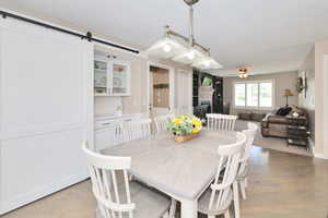 Dining area featuring ceiling fan, light wood-type flooring, a barn door, and baseboards