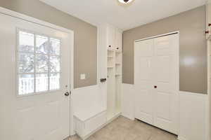 Mudroom with a wainscoted wall, healthy amount of natural light, and light tile patterned flooring