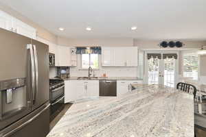 Kitchen featuring stainless steel appliances, a sink, french doors, white cabinetry, and recessed lighting