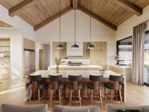 Kitchen featuring hanging light fixtures, light wood-style flooring, light stone countertops, high vaulted ceiling, and built in fridge