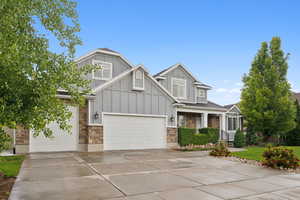 Craftsman inspired home with stone siding, concrete driveway, board and batten siding, and an attached garage