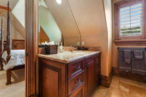 Bathroom with stone tile floors, vanity, connected bathroom, and baseboards