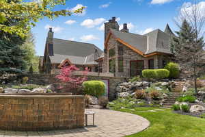 View of home's exterior featuring stairway, a chimney, a patio, a yard, and stone siding