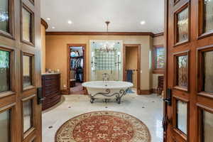 Full bath with baseboards, a freestanding bath, crown molding, a chandelier, and a walk in closet
