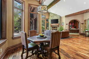 Dining area featuring beam ceiling, baseboards, high vaulted ceiling, hardwood / wood-style floors, and a fireplace