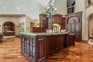 Bar area with arched walkways, a high ceiling, light wood-style floors, baseboards, and a chandelier