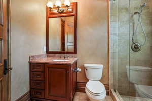 Full bath with toilet, a tile shower, vanity, and a chandelier