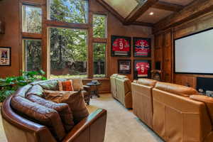 Cinema room with plenty of natural light, beamed ceiling, and light colored carpet
