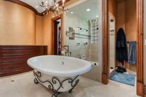 Bathroom featuring a freestanding bath, a chandelier, tiled shower, and tile patterned flooring