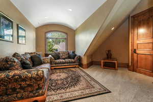 Carpeted living area with lofted ceiling, baseboards, and recessed lighting