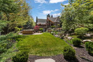 View of green lawn featuring a patio area and an outdoor fire pit
