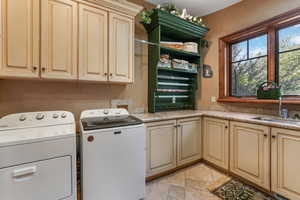 Laundry room featuring cabinet space, separate washer and dryer, and stone tile floors